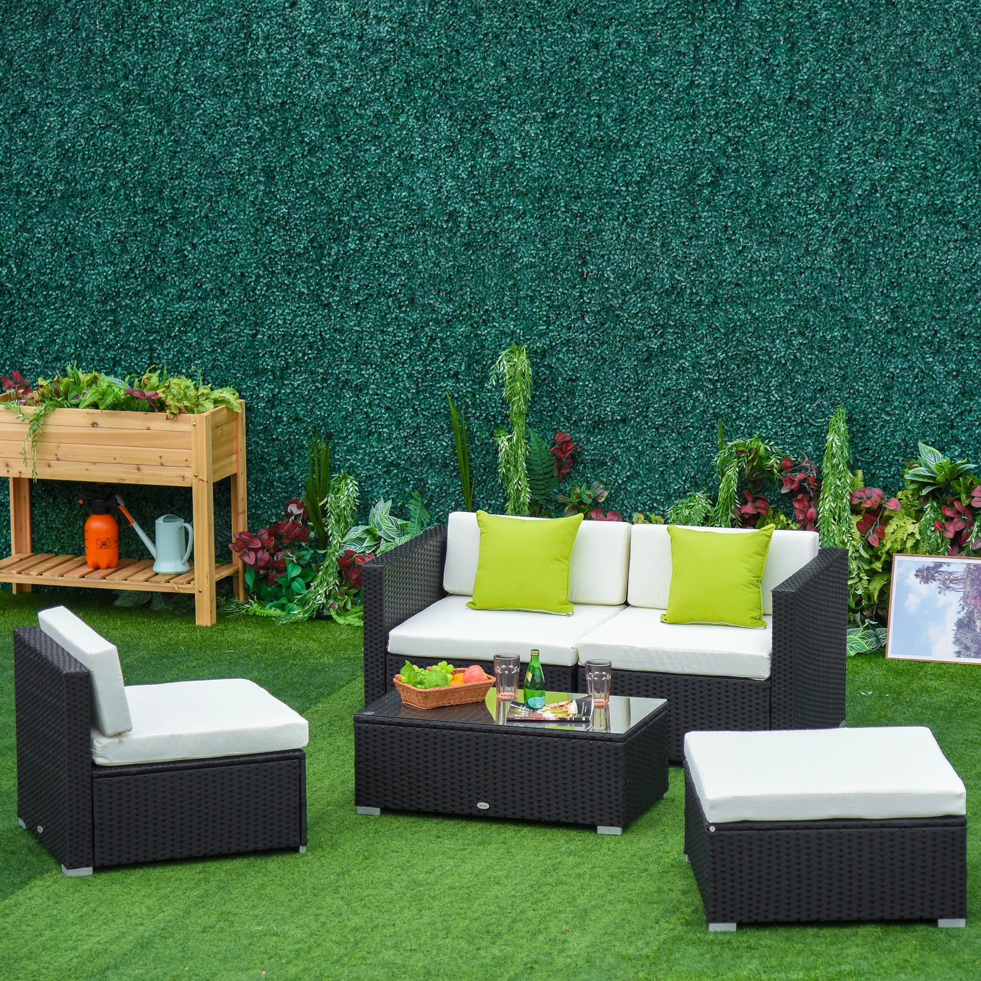 Outdoor patio furniture set with green cushions on a grassy area.