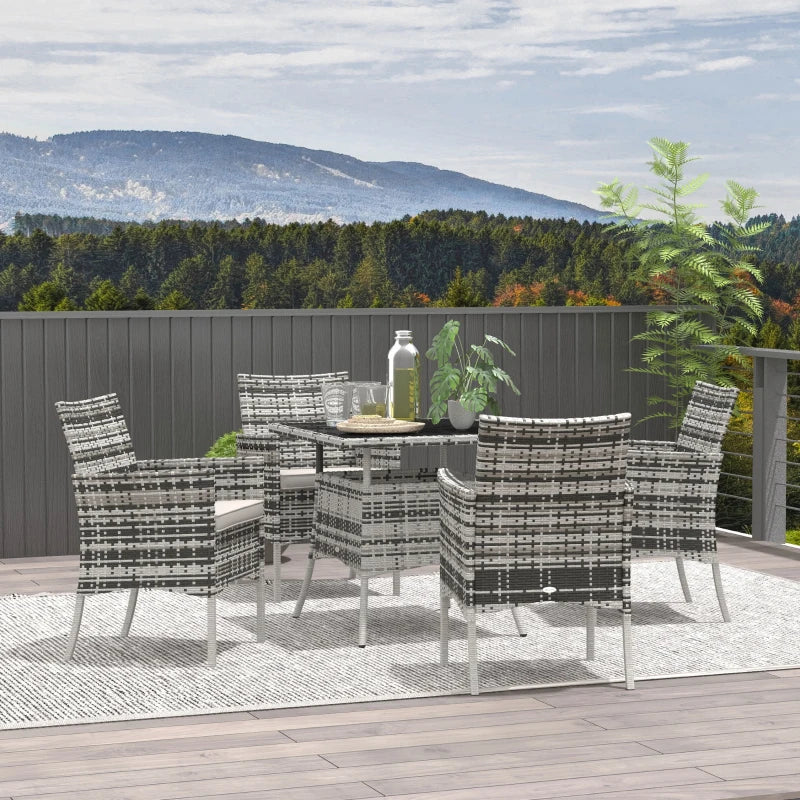 Outdoor dining set with table and chairs on a balcony with a scenic view of mountains and trees.