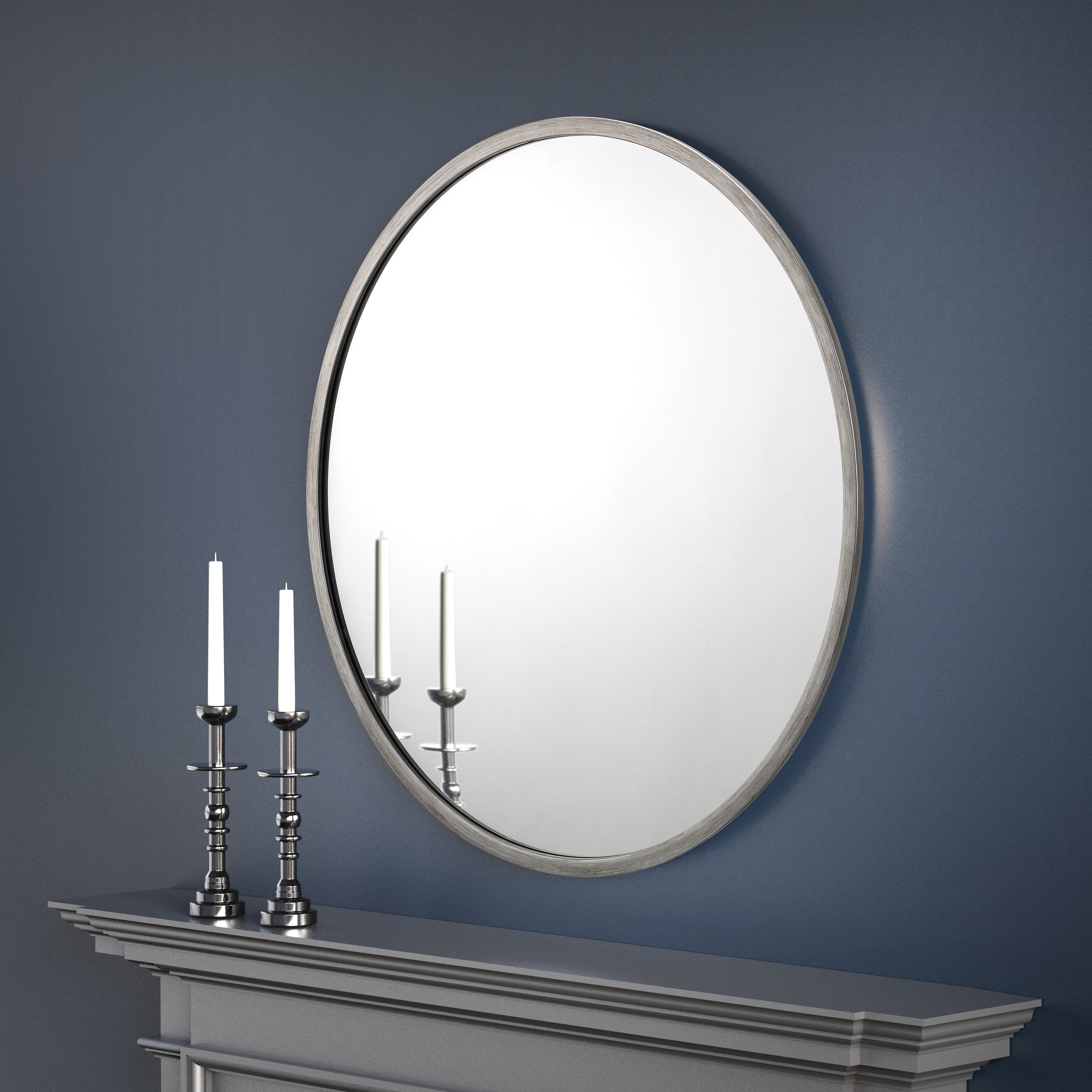 Round mirror on a dark blue wall above a fireplace with candles.