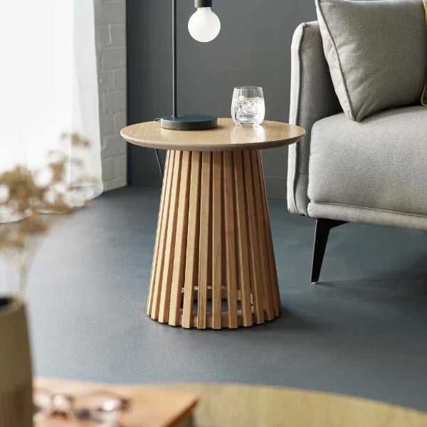 Wooden side table with a glass and lamp in a living room setting