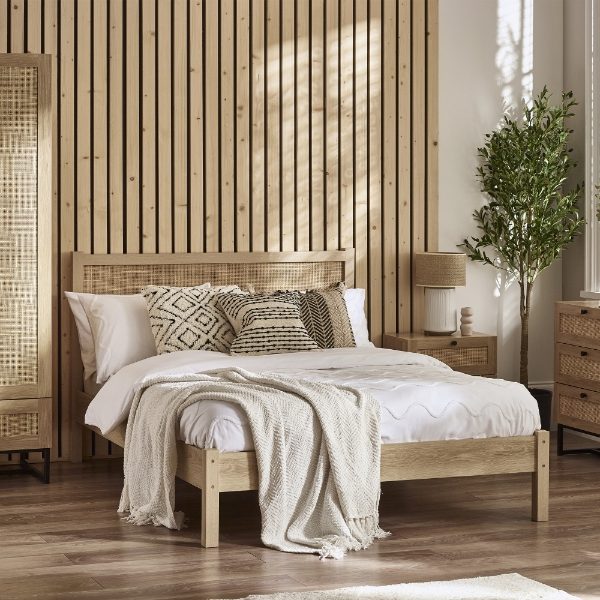 Wooden bed with decorative pillows and a lamp in a bedroom setting.