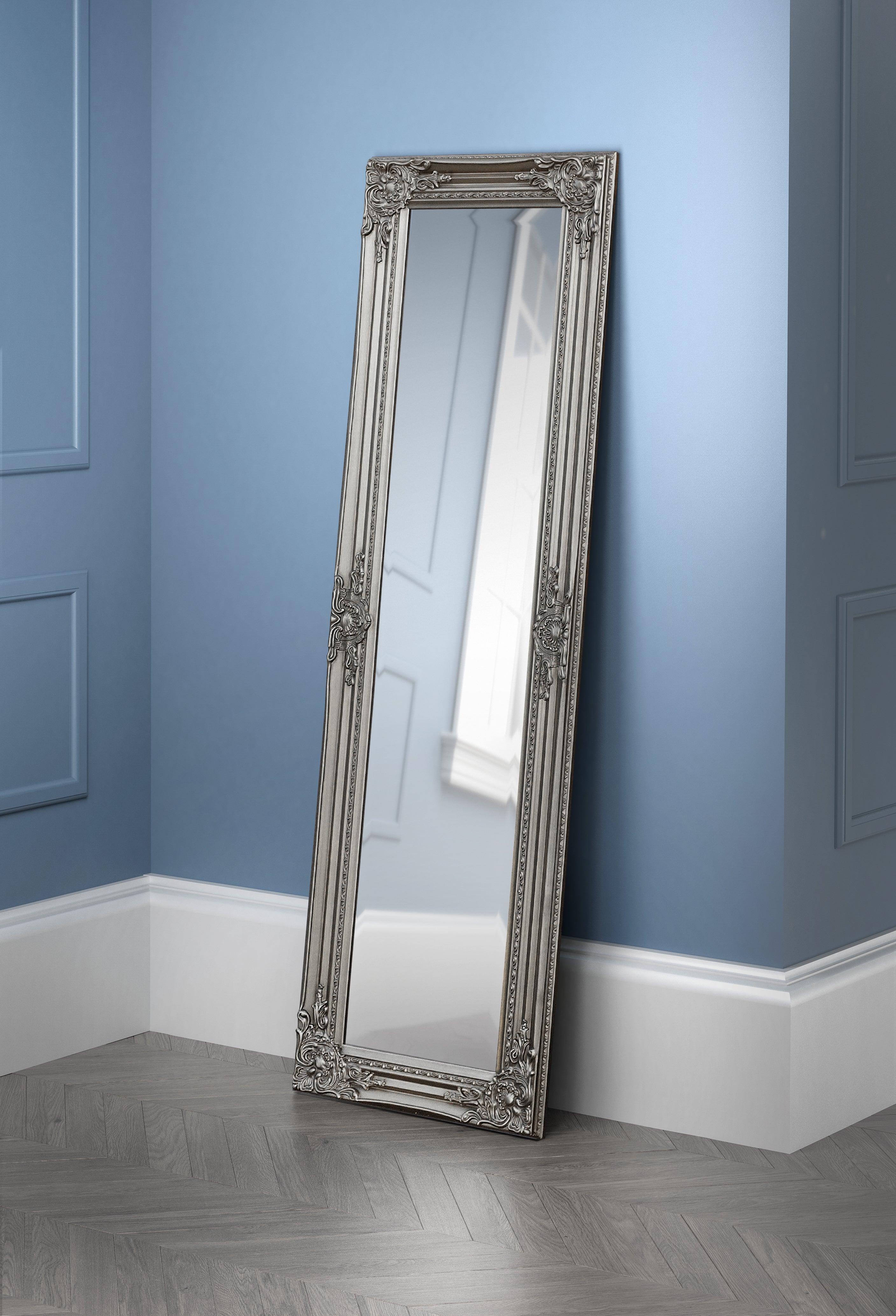 Decorative full-length mirror with ornate frame against a blue wall.