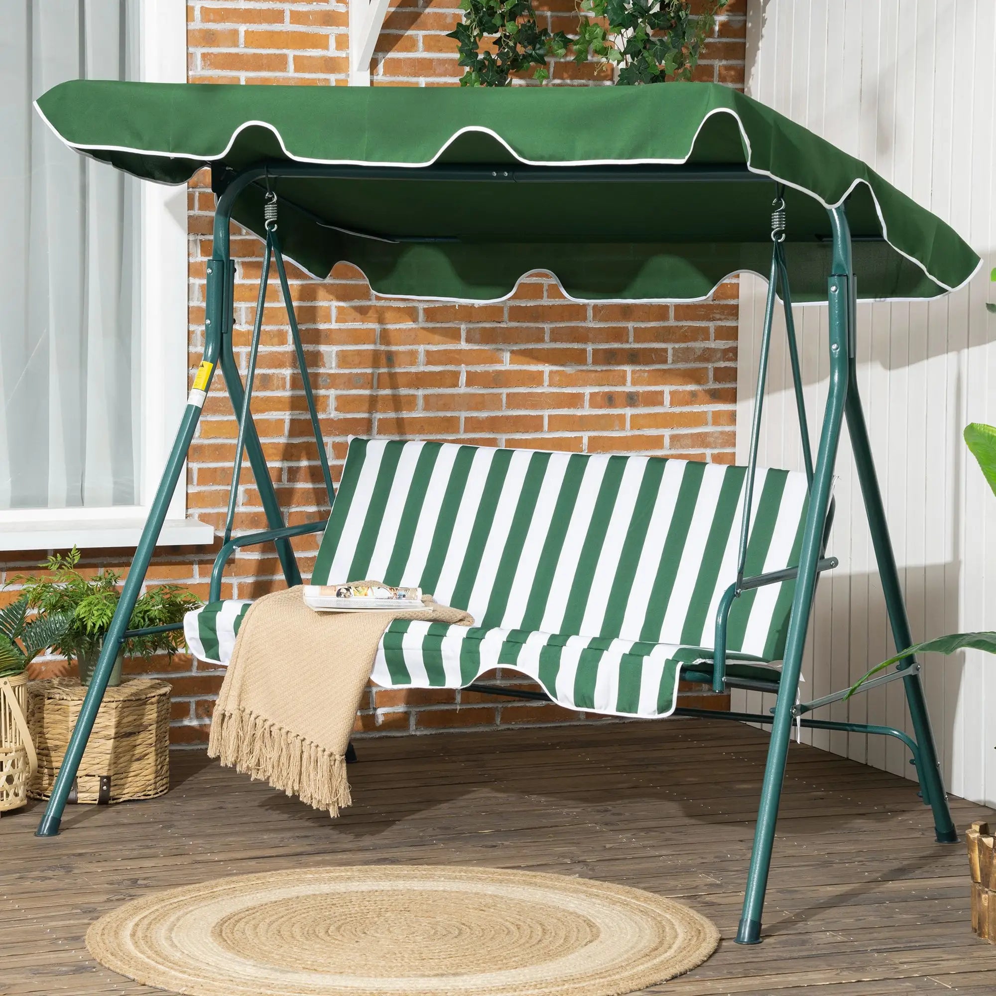 Green and white striped swing with canopy on a wooden deck.