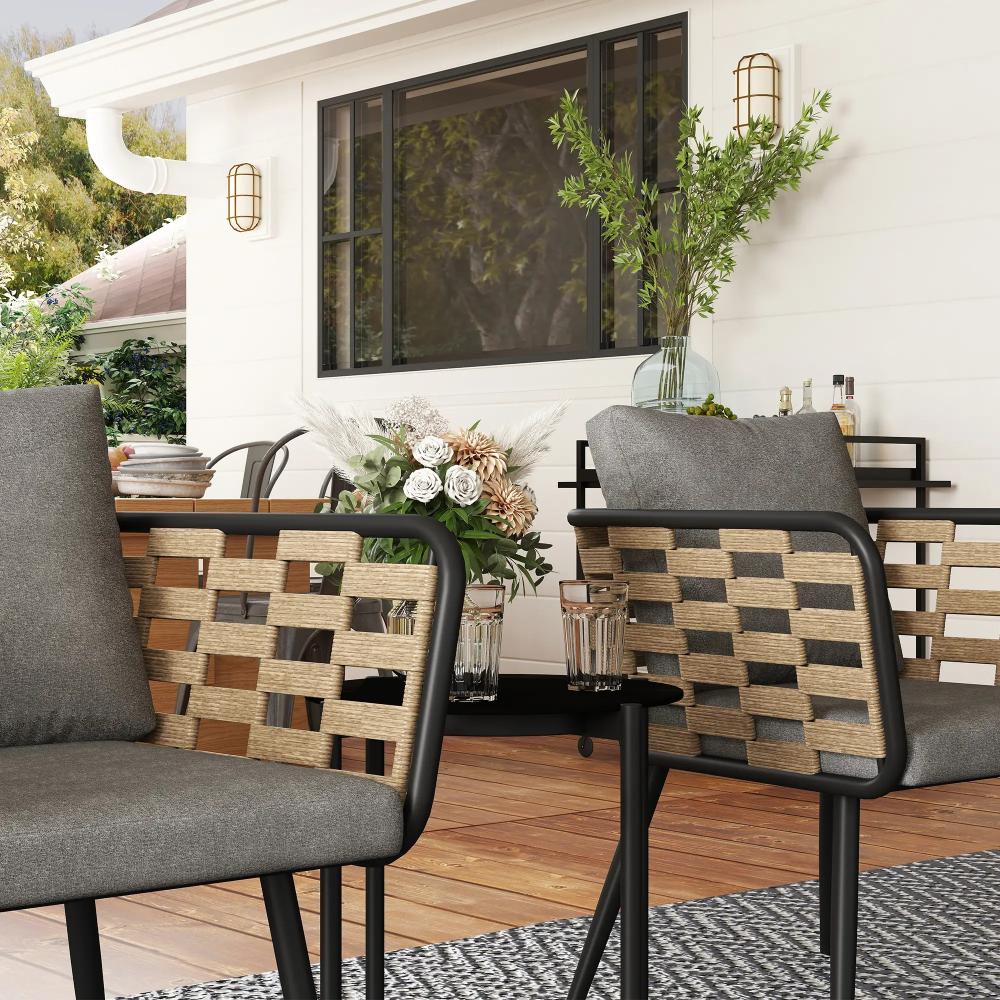 Outdoor patio setting with gray chairs, woven backrests, and a white house in the background.
