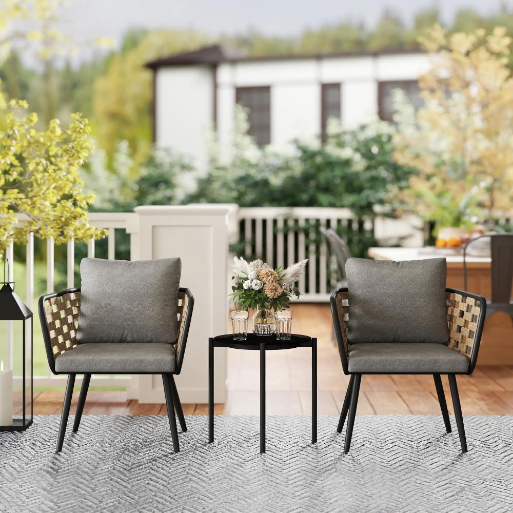 Outdoor patio set with two chairs and a small table on a patio with a blurred background of a house and garden.