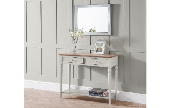 Console table with mirror and decor items against a gray paneled wall.