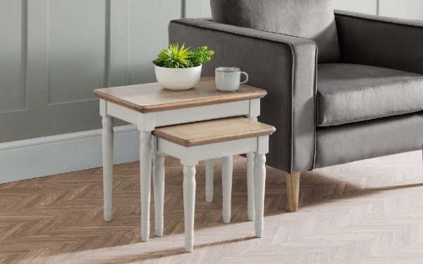 Nest of two tables with a plant and mug next to a gray sofa.