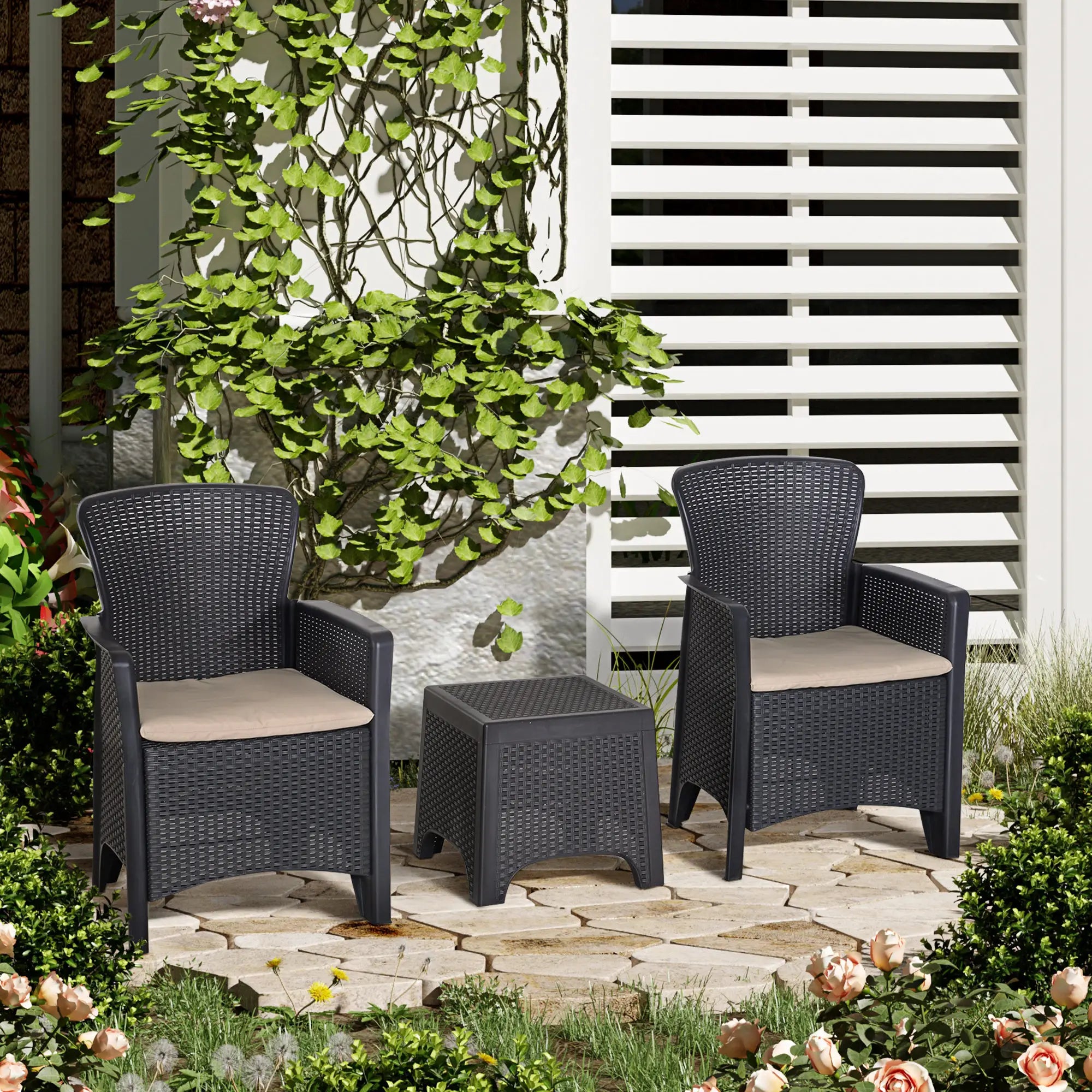 Two dark wicker chairs with beige cushions and a matching ottoman on a stone patio.
