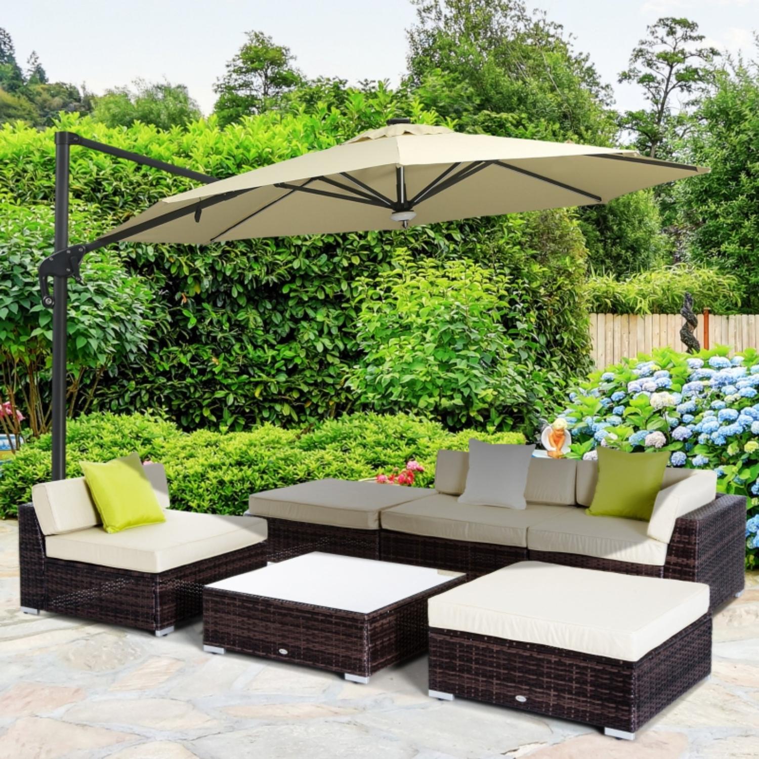 Outdoor patio set with sectional sofa, ottomans, and umbrella in a garden setting.
