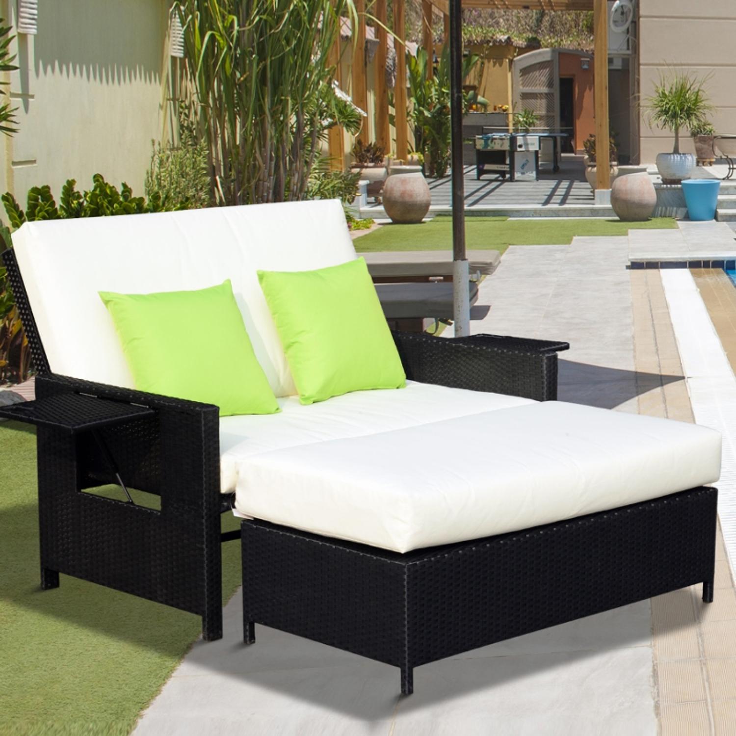 Outdoor patio set with black frame, white cushions, and green pillows in a garden setting.