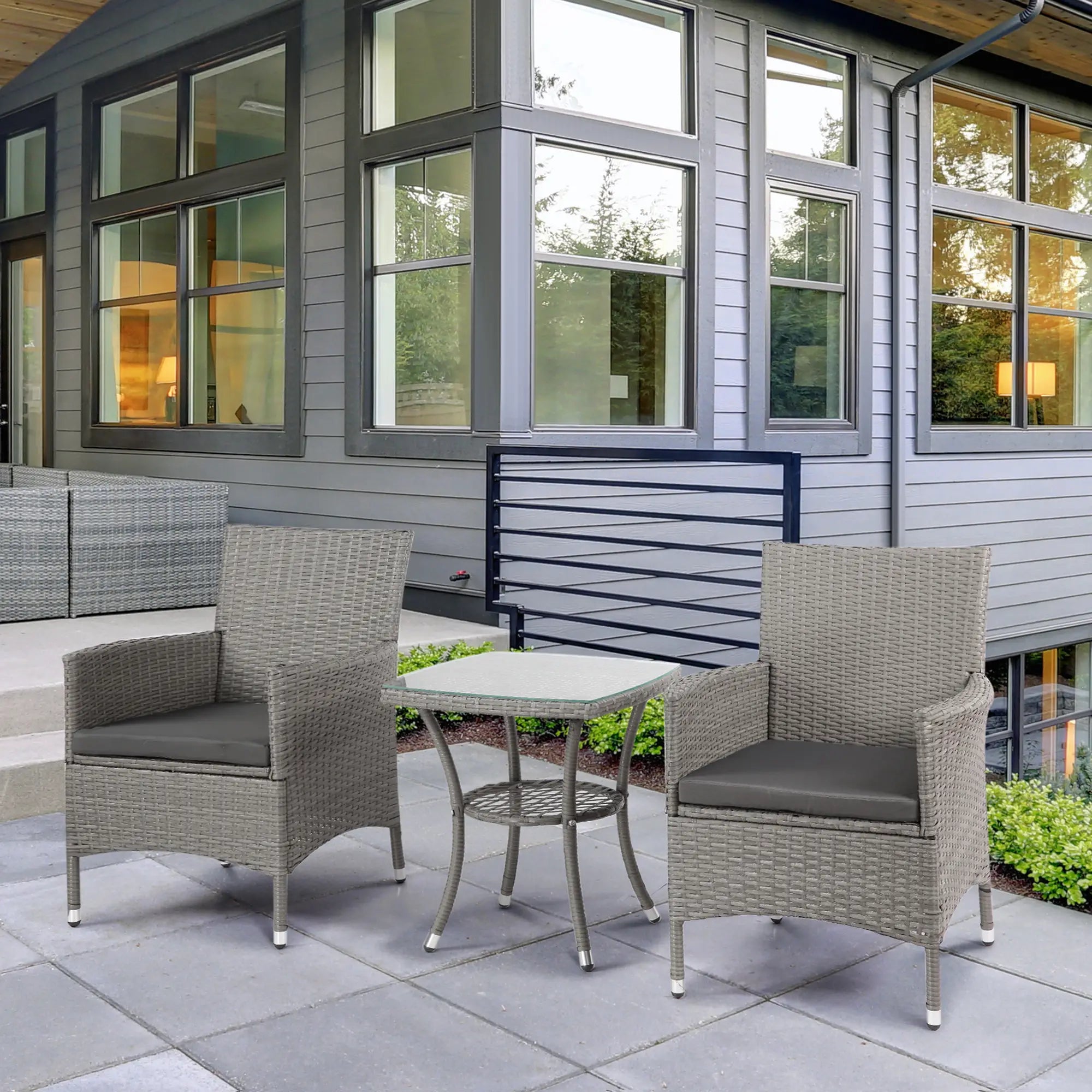 Outdoor patio set with two chairs and a table in front of a modern house.
