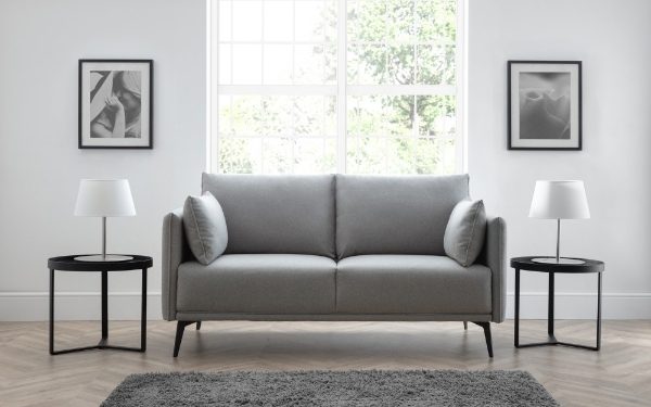 Gray sofa in a room with two side tables and framed pictures on the wall.