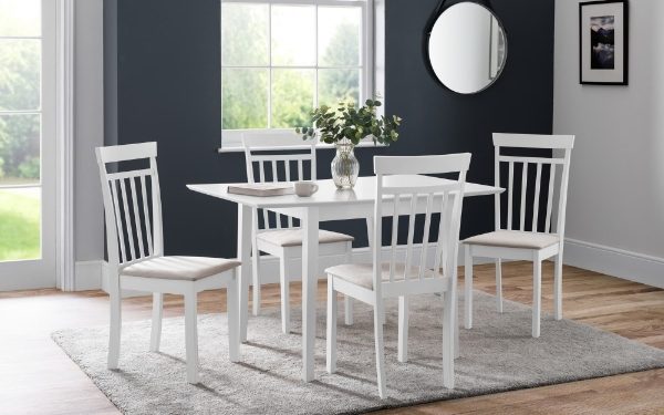 Dining room with a white table and chairs in a room with large windows.