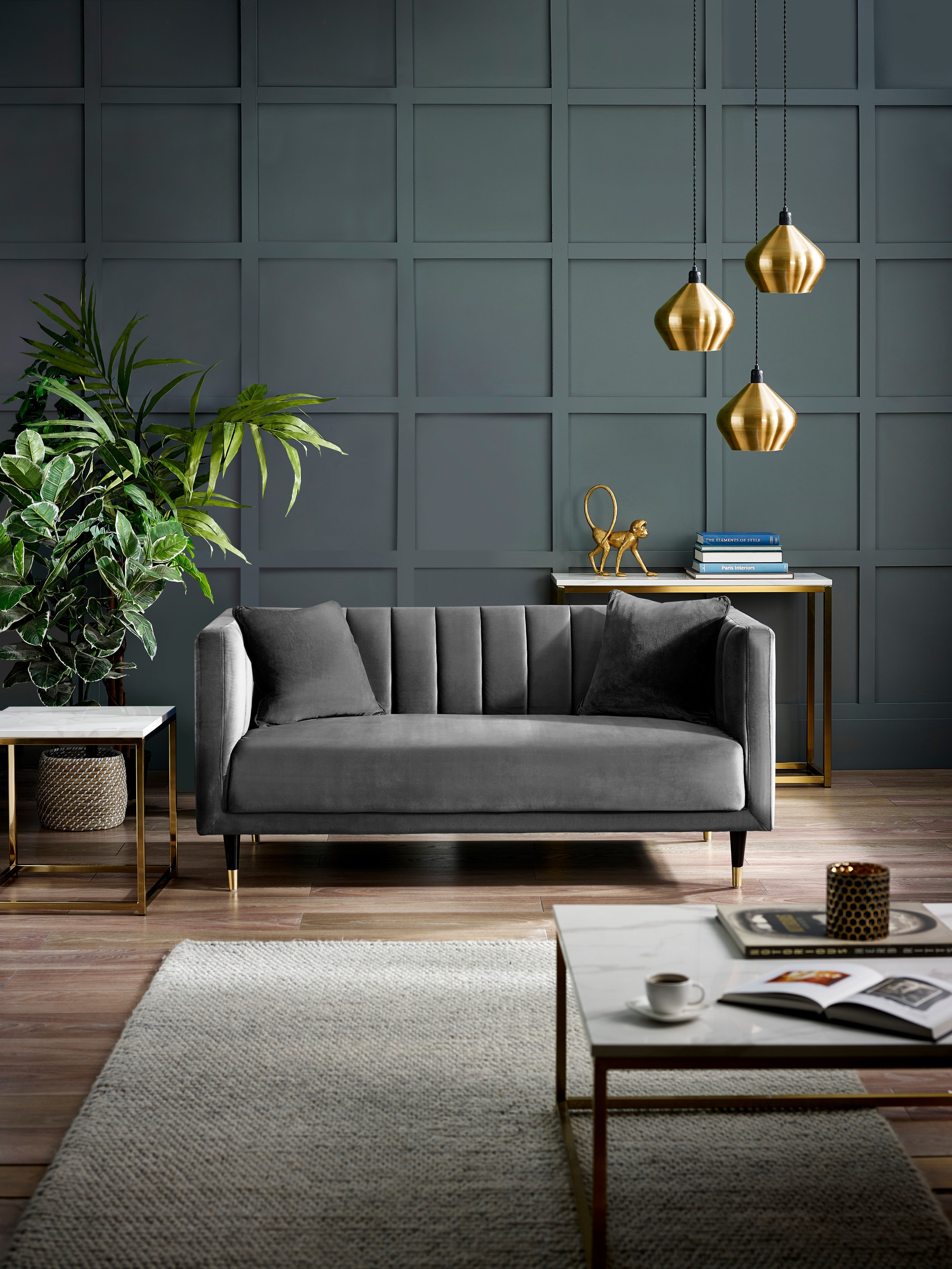 Modern living room with a gray sofa, coffee table, and decorative items against a dark paneled wall.
