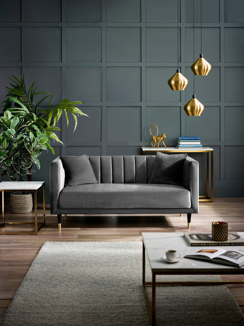 Modern living room with a gray sofa, coffee table, and decorative items against a dark paneled wall.