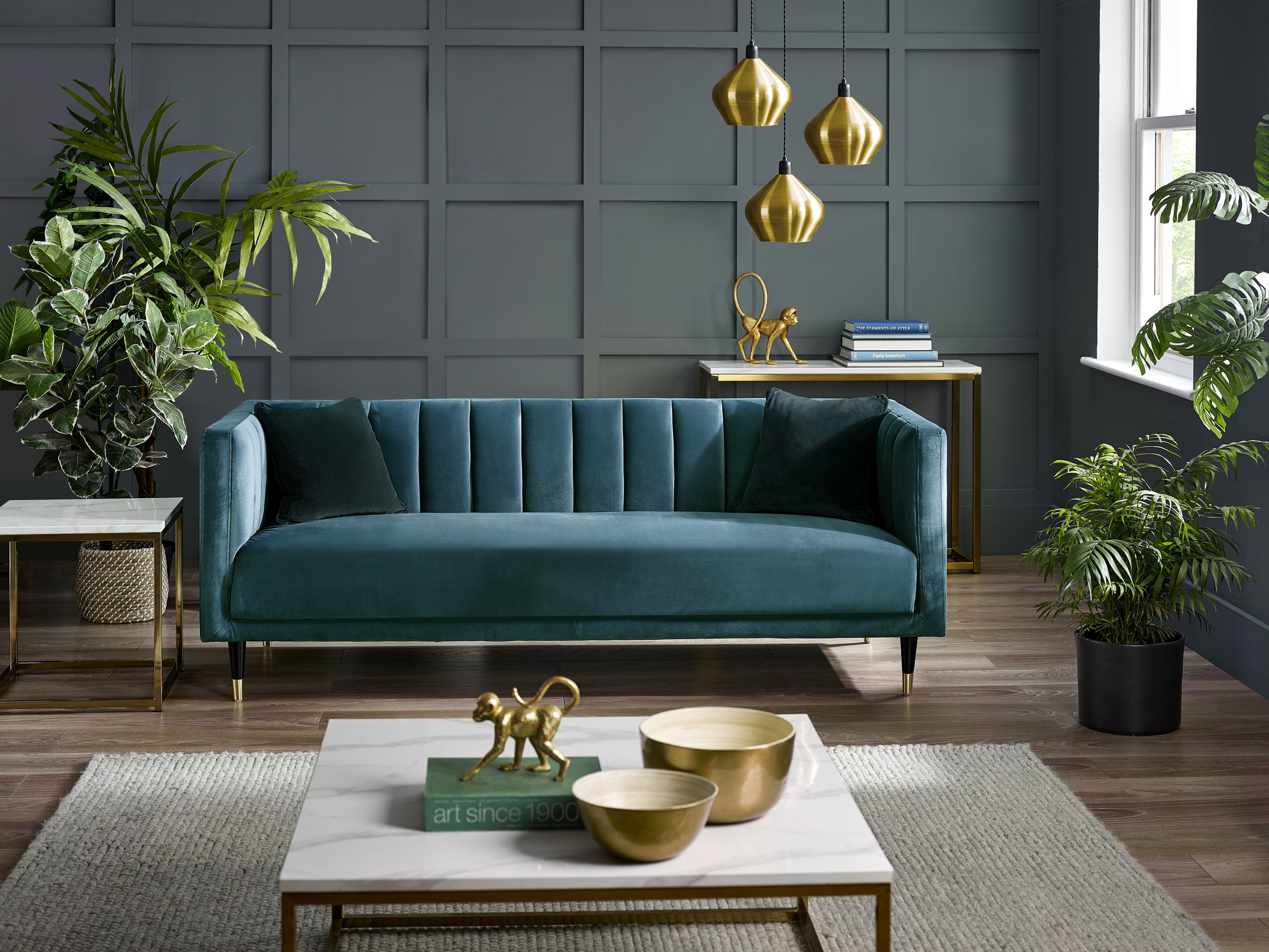 Modern living room with a teal sofa, gold decor, and plants.