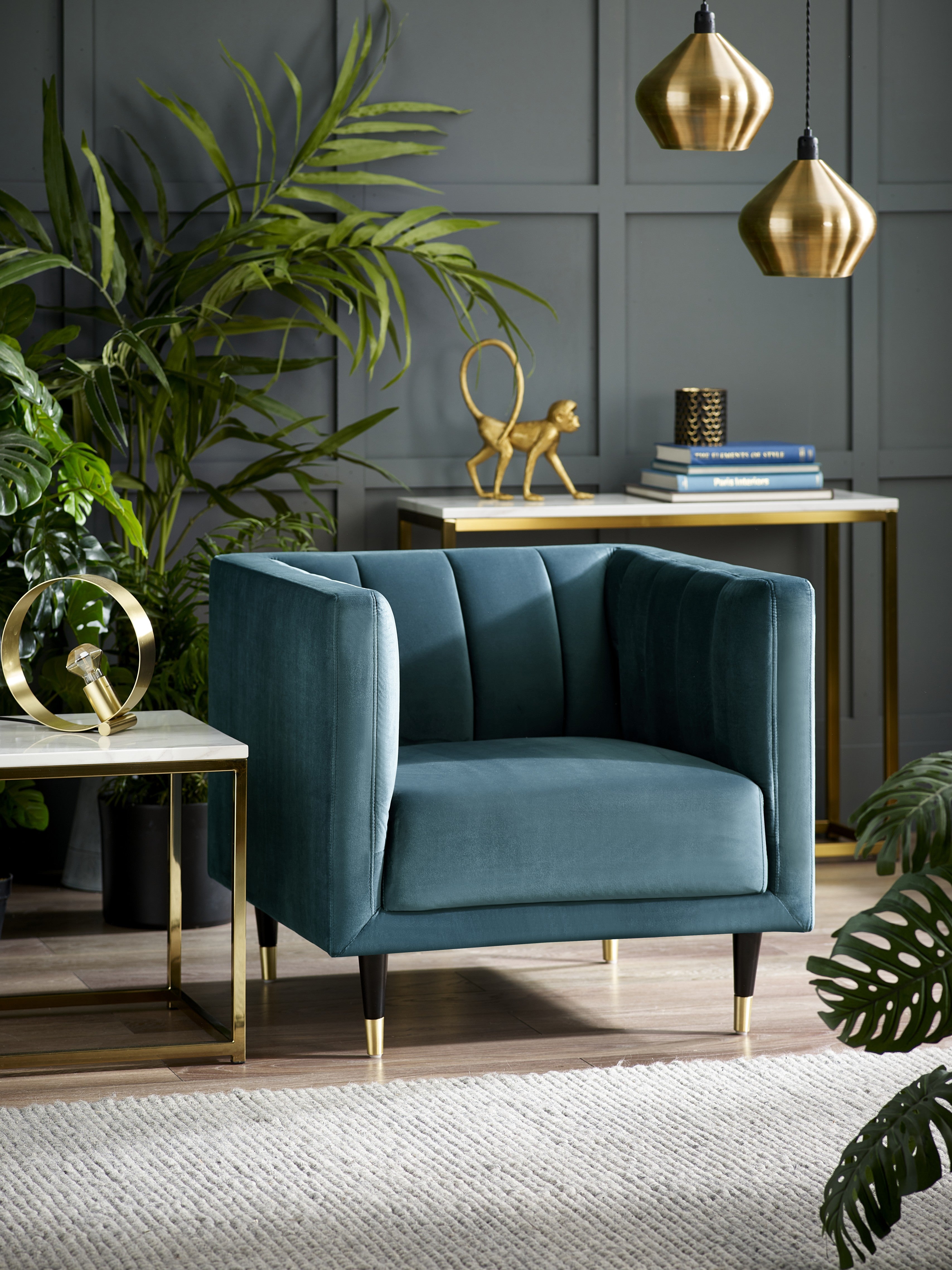 Blue armchair in a stylish living room with plants and decorative items.