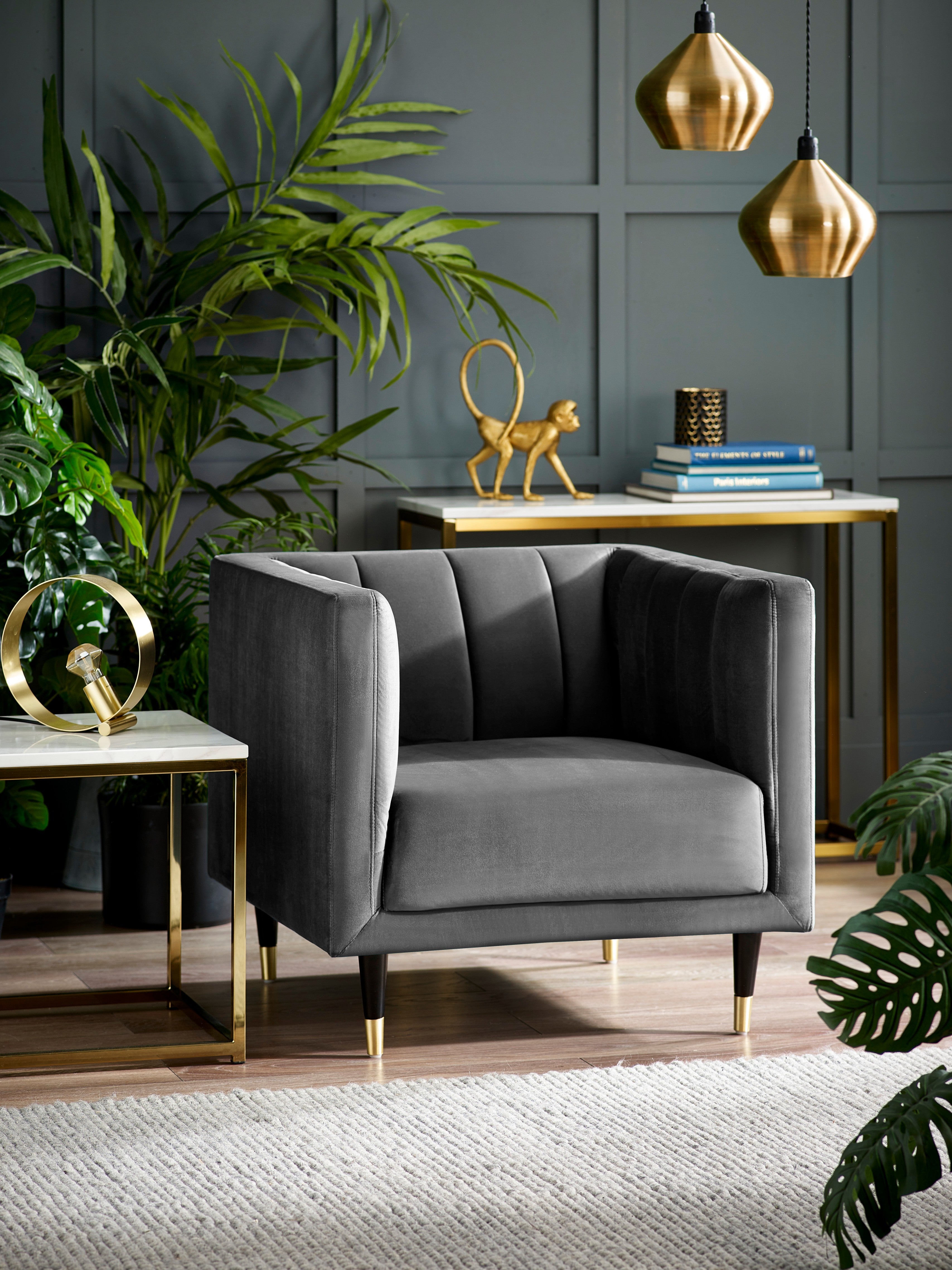 Gray armchair in a stylish room with plants and decorative items.
