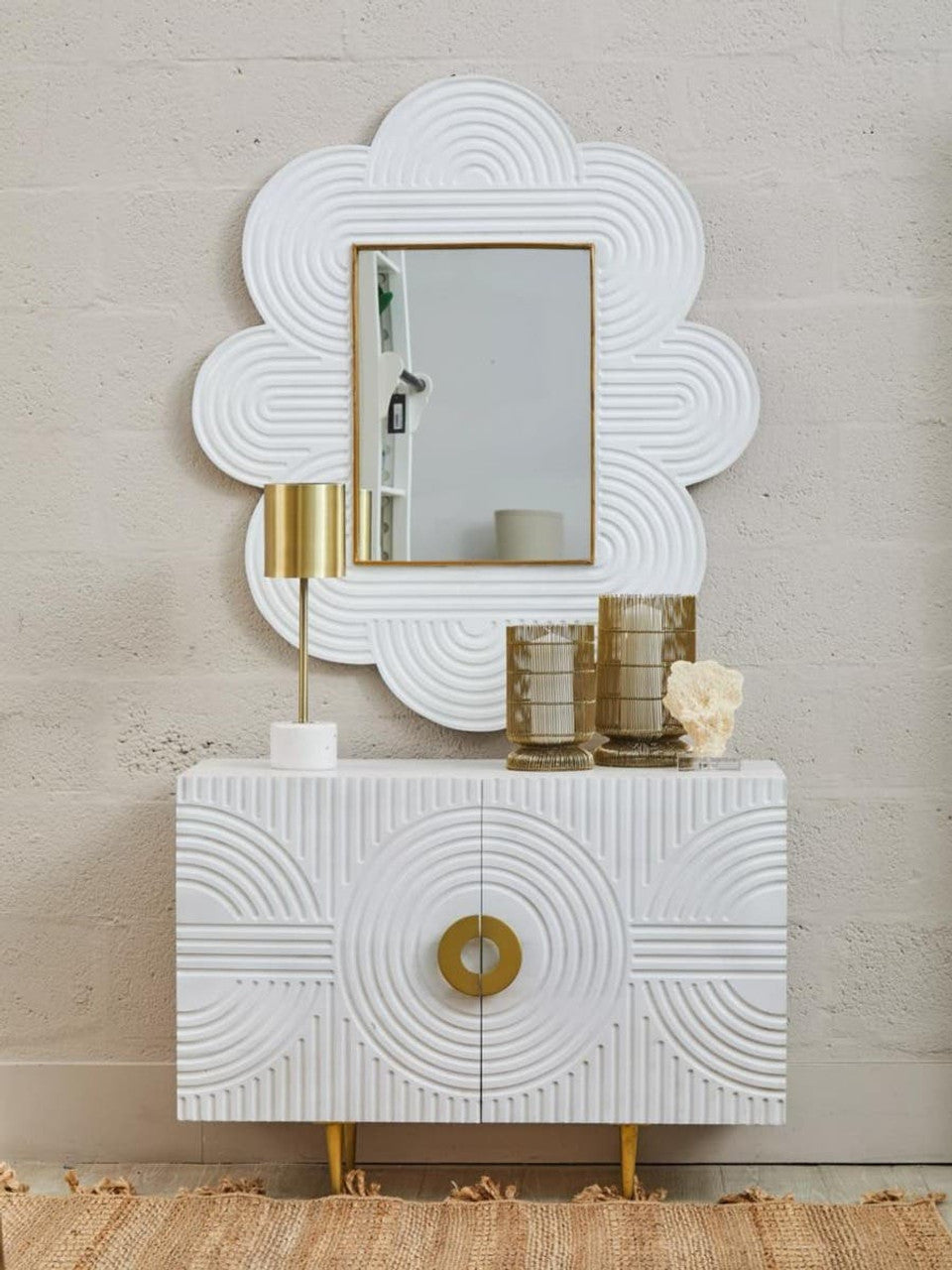 Decorative white console table with gold accents and matching wall mirror against a beige wall.