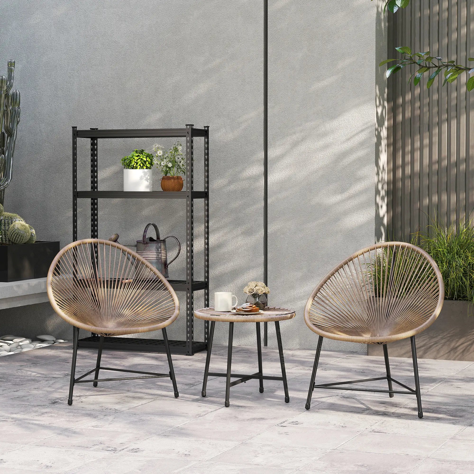 Two wicker chairs with a small round table on a patio with a gray wall and plants in the background.