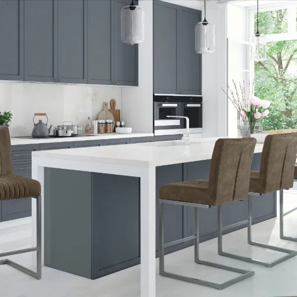 Modern kitchen with gray cabinets, white island, and brown stools.