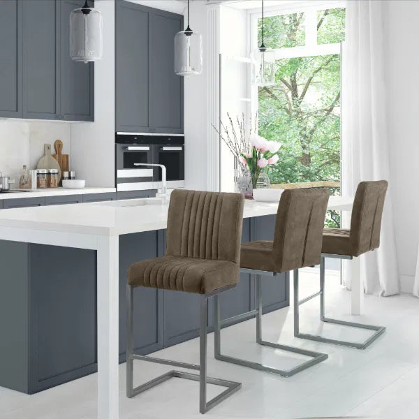 Modern kitchen with gray cabinets, white island, and brown bar stools.