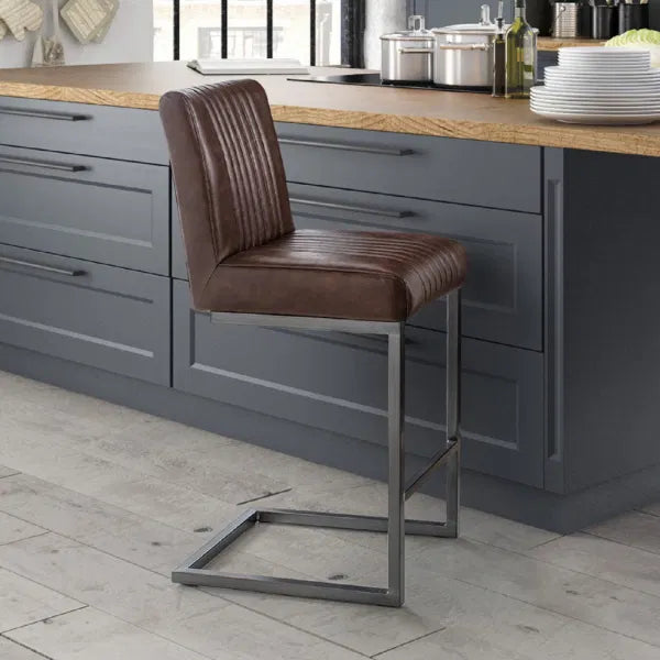 Brown leather bar stool in a modern kitchen setting with gray cabinets and wooden countertops.