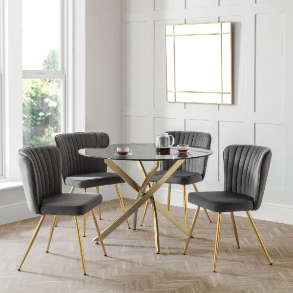 Dining room with a round glass table and four gray chairs with gold legs.