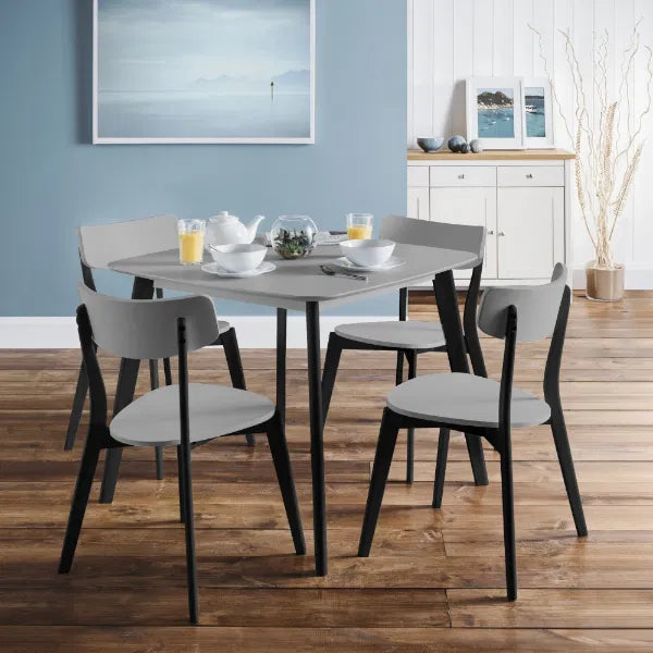 Dining table set with chairs in a room with a blue wall and wooden floor.