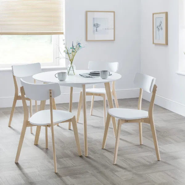 Dining room with a round table and four chairs on a wooden floor.