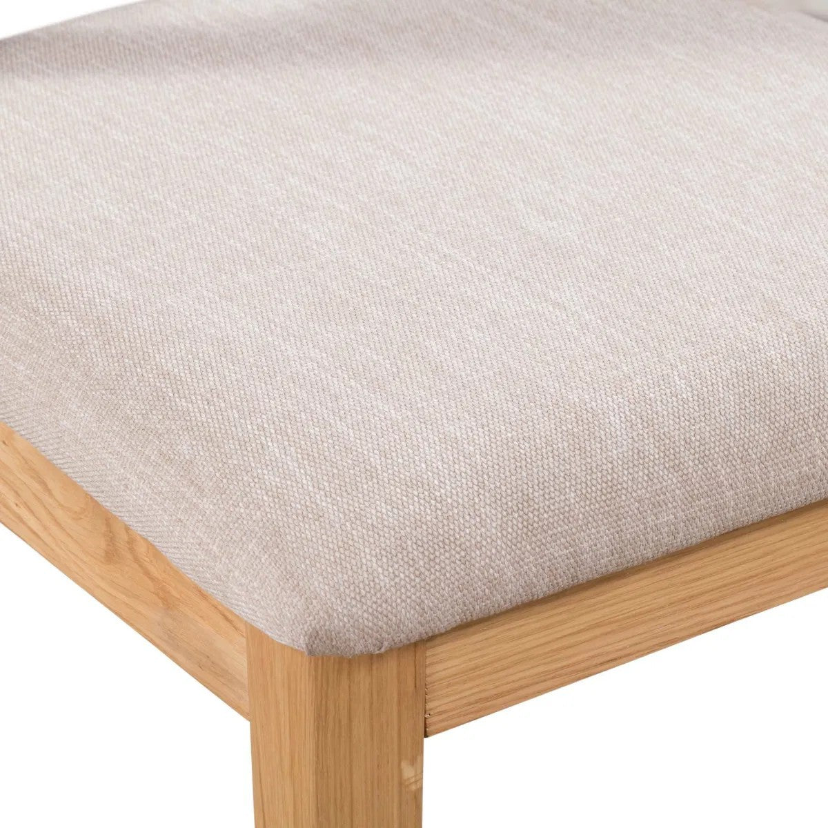 Wooden stool with a beige cushioned seat on a white background