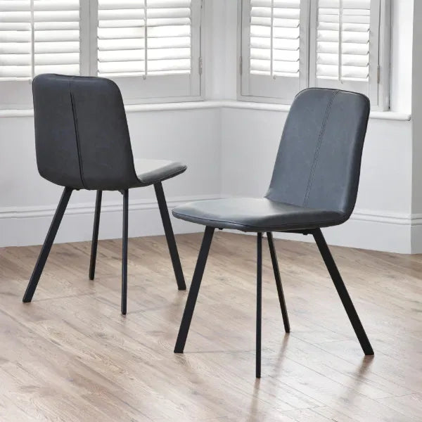 Two black chairs on a wooden floor with white walls and windows in the background.