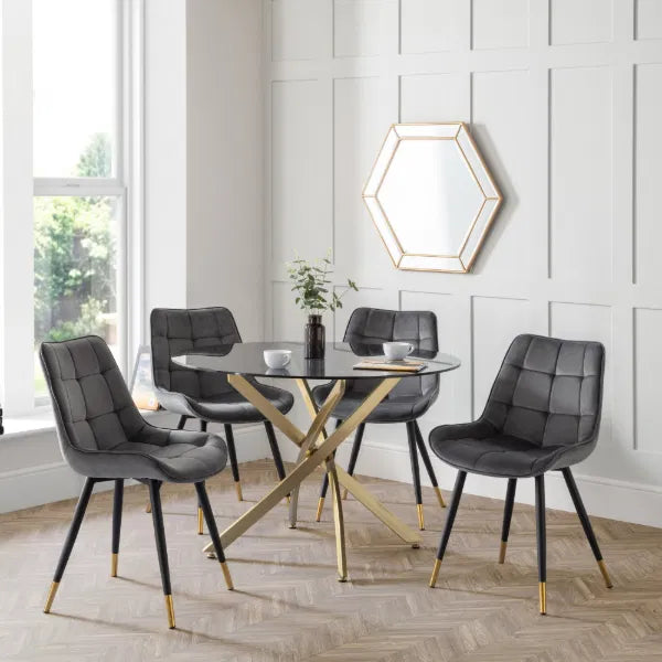 Dining room with a glass table and gray chairs against a white paneled wall.