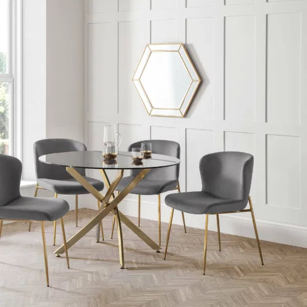 Dining room with a round glass table and gray chairs against a white paneled wall.