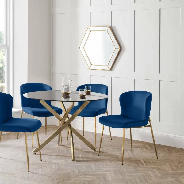 Dining room with a round table and blue chairs against a white paneled wall.