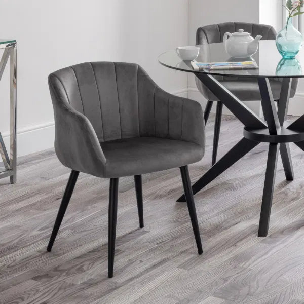Gray upholstered chair in a modern dining room setting with a glass table.