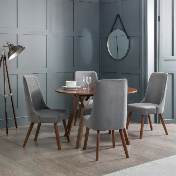 Dining room with a round wooden table and gray chairs against a gray paneled wall.