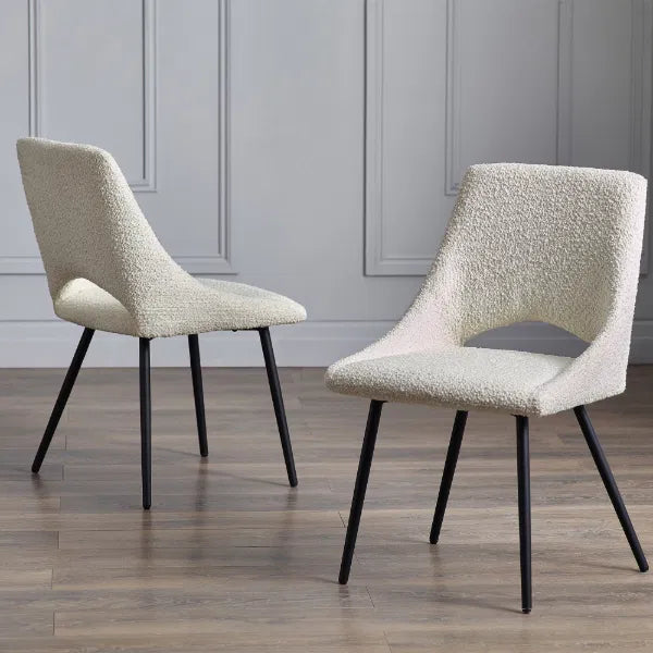 Two textured chairs with black legs on a wooden floor against a gray paneled wall.