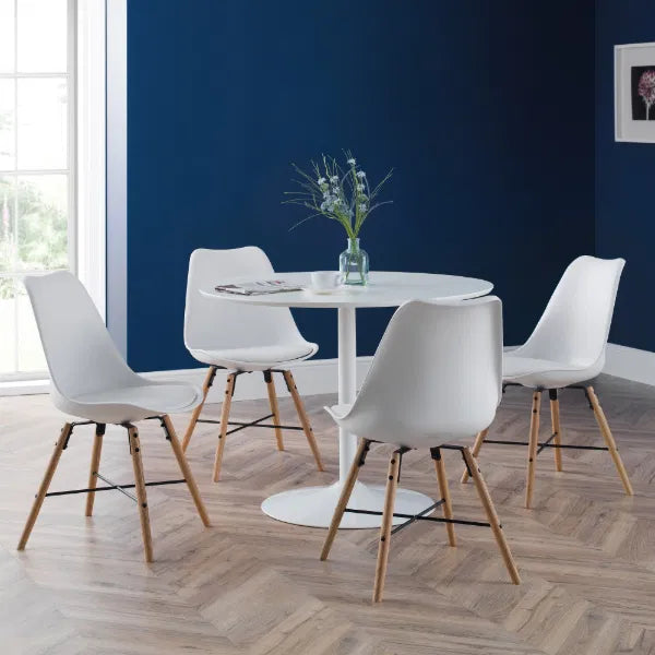 Modern dining room with white chairs and a round table against a blue wall.