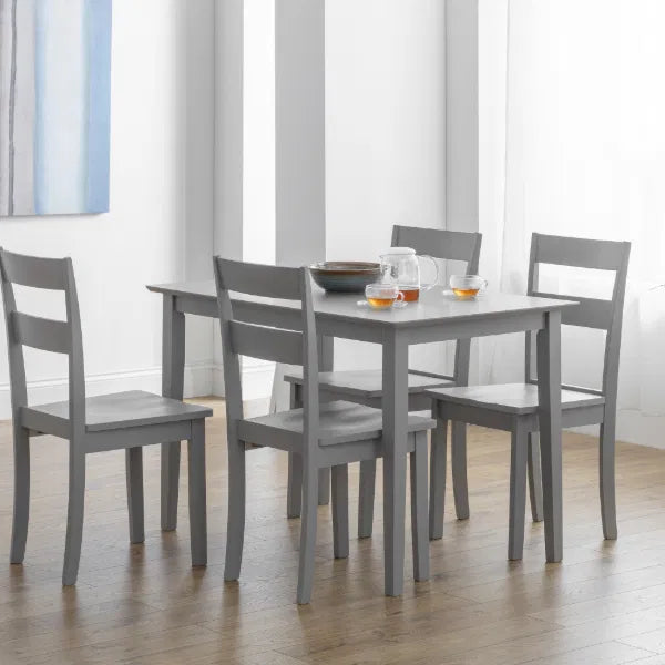 Gray dining table with four matching chairs in a room with light-colored walls and wooden flooring.