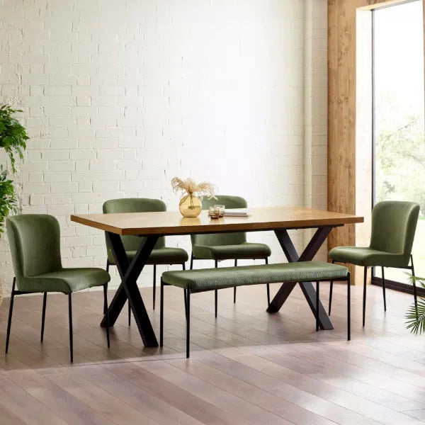 Dining room with wooden table and green chairs against a white brick wall.