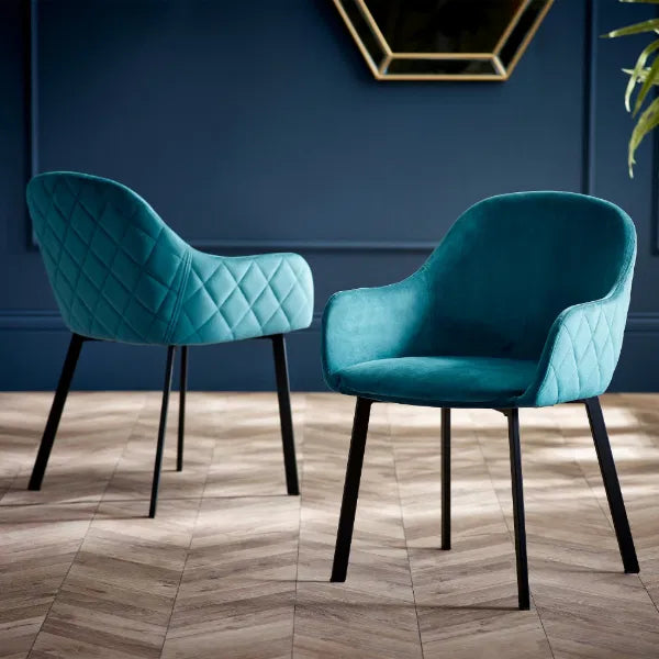 Two teal chairs with black legs on a wooden floor against a blue wall.