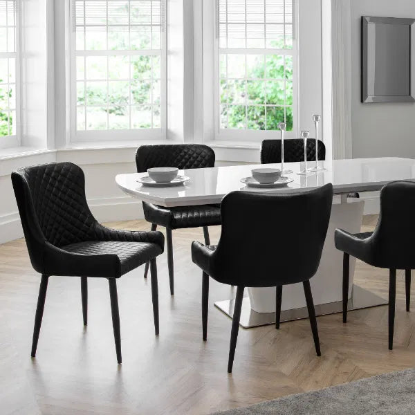 Dining room with a white table and black chairs in a bright room.