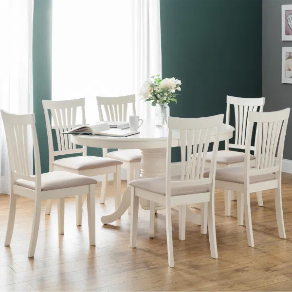 Dining room with white table and chairs against a green wall.