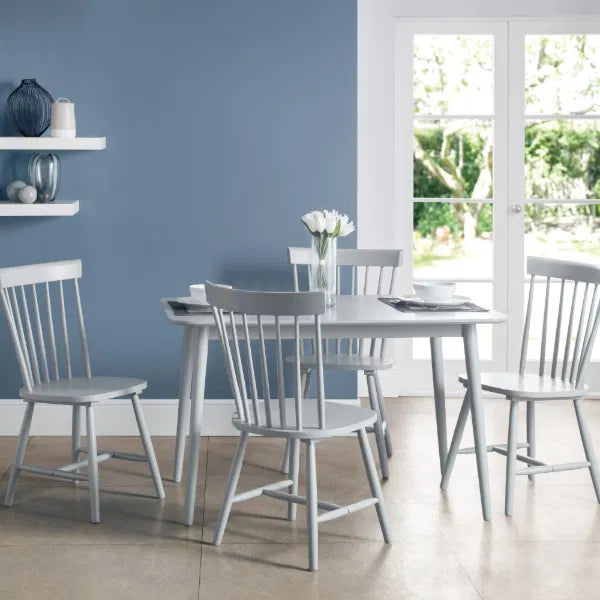Dining room with grey chairs and table against a blue wall.