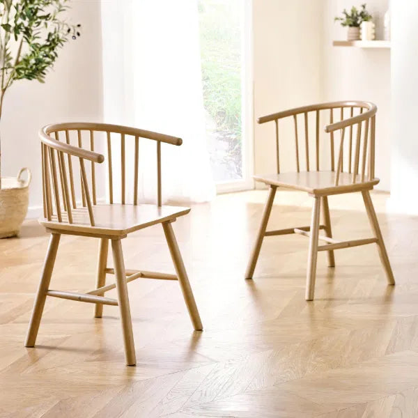 Two wooden chairs in a bright room with light wood flooring.