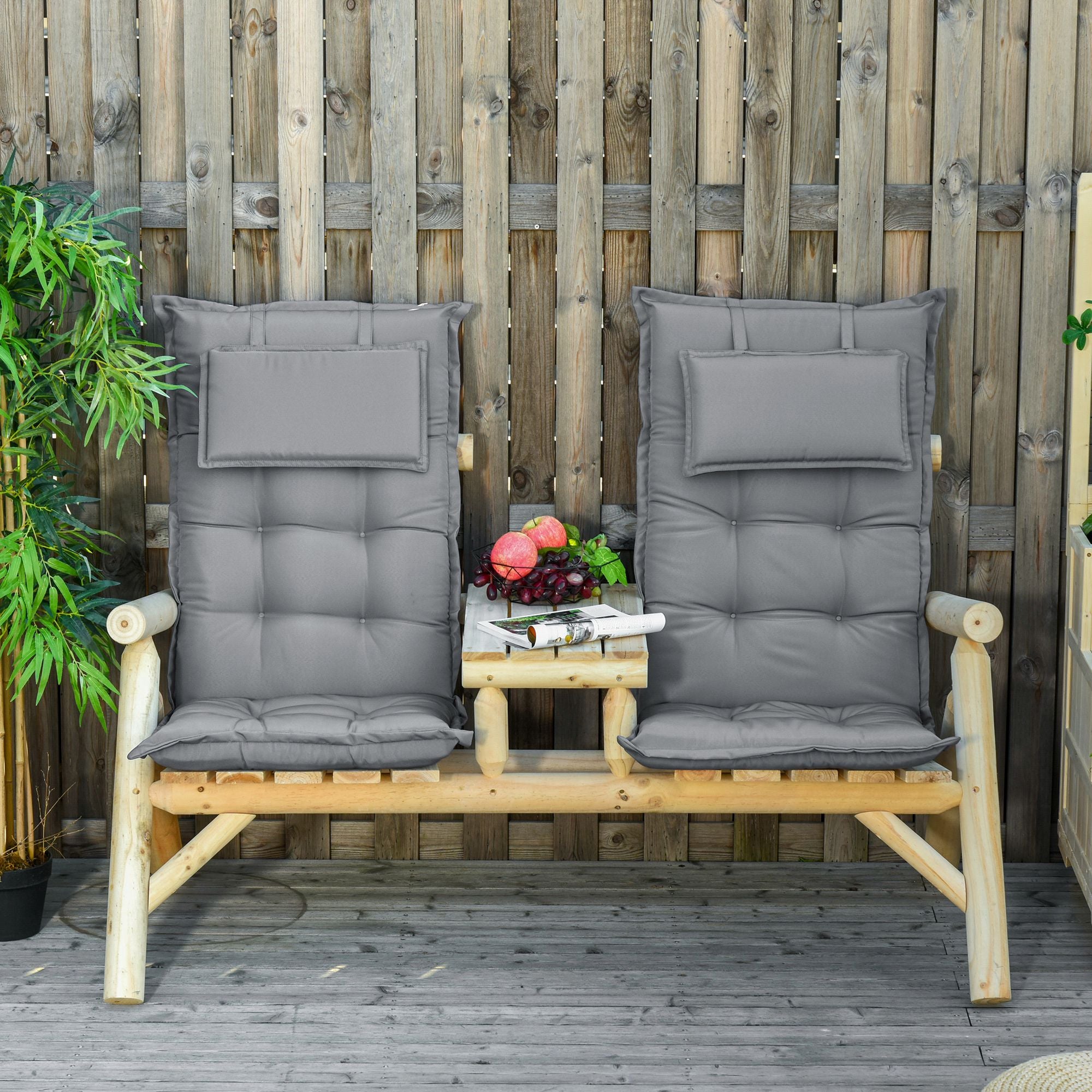Two wooden chairs with gray cushions on a wooden deck against a wooden fence.