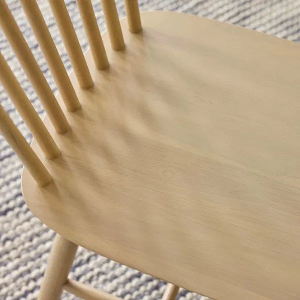 Close-up of a wooden chair seat and backrest on a textured surface