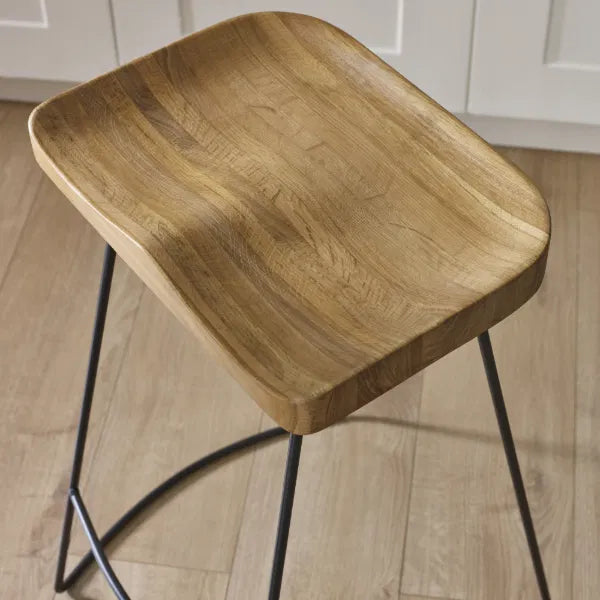 Wooden stool with black metal legs on a wooden floor