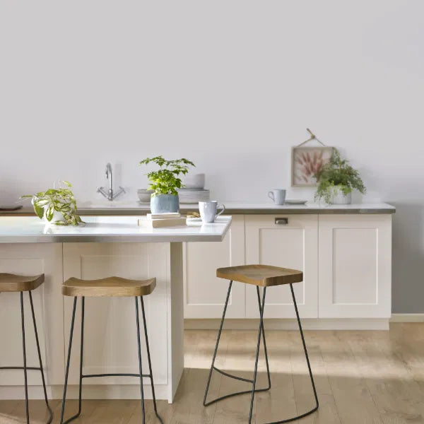 Modern kitchen with white island, stools, and decorative plants.